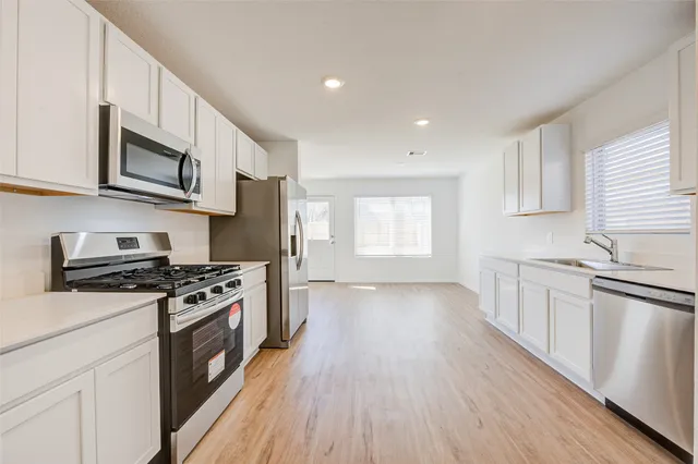 a kitchen with stainless steel appliances granite countertop hardwood floor sink stove and wooden cabinets