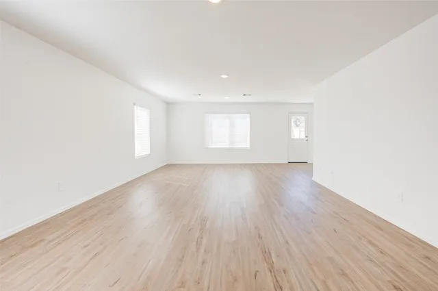 an empty room with wooden floor and window