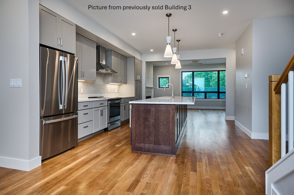 10 Hawley Street, Unit 4C Northampton, MA 01060 - Photo 8 of 23 a kitchen with stainless steel appliances granite countertop a refrigerator a sink dishwasher a stove and a dining table with wooden floor