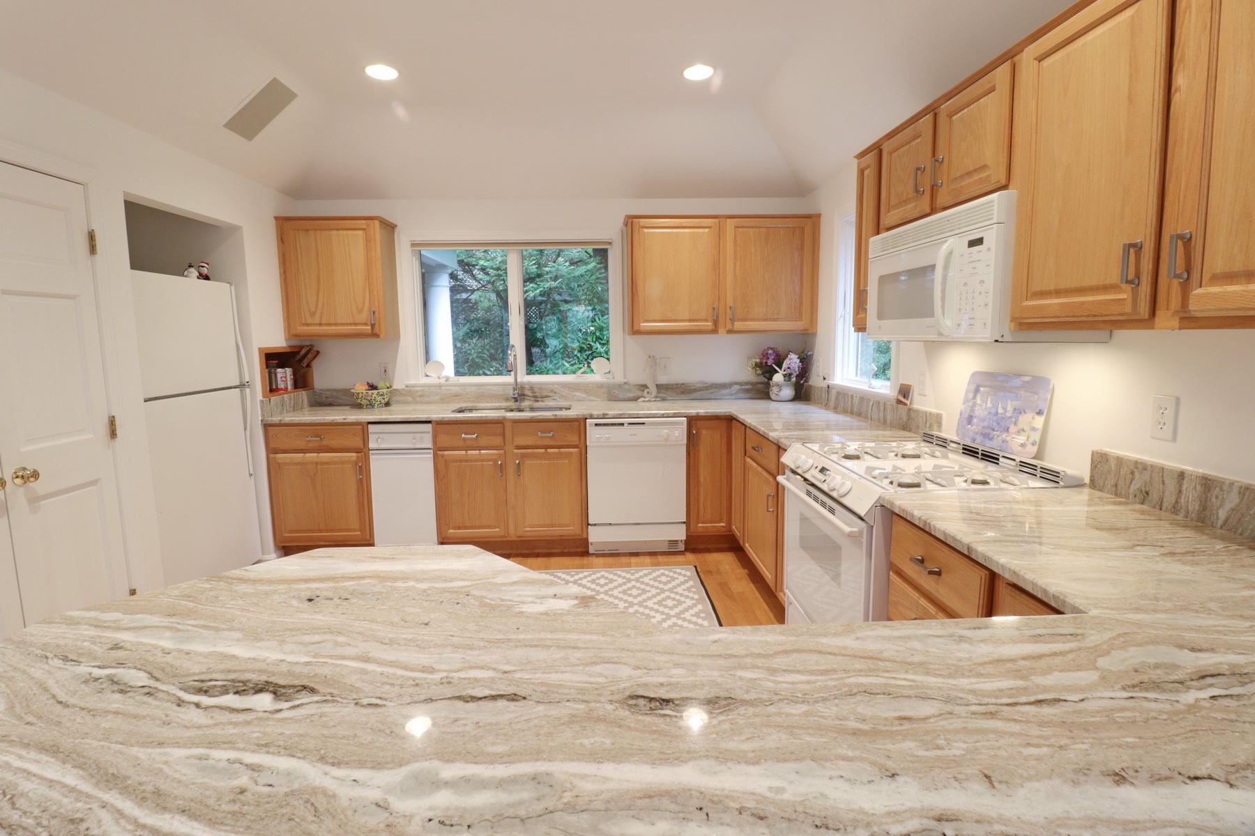 120 Fells Pond Road Mashpee, MA 02649 - Photo 18 of 42 a kitchen with stainless steel appliances granite countertop a stove top oven a sink a refrigerator and white cabinets with wooden floor