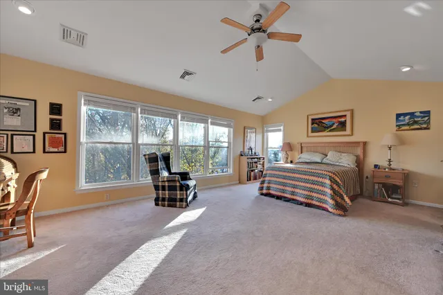 a bedroom with a bed a large window with table and chair