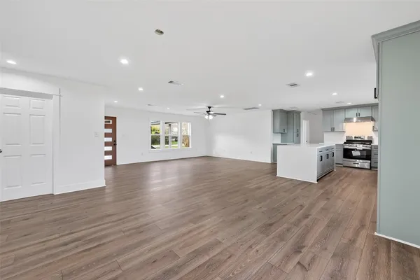 an empty room with wooden floor and a ceiling fan