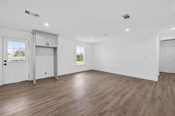 a view of an empty room with wooden floor and a window