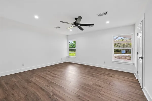 a view of empty room with wooden floor and fan
