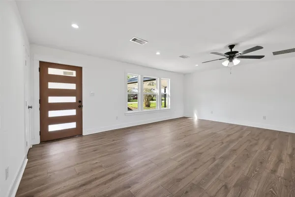 a view of an empty room with a window and wooden floor