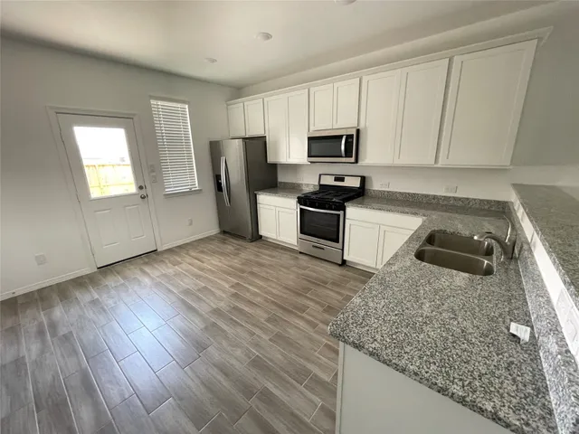 a kitchen with stainless steel appliances granite countertop a sink dishwasher a stove with wooden floor and cabinets