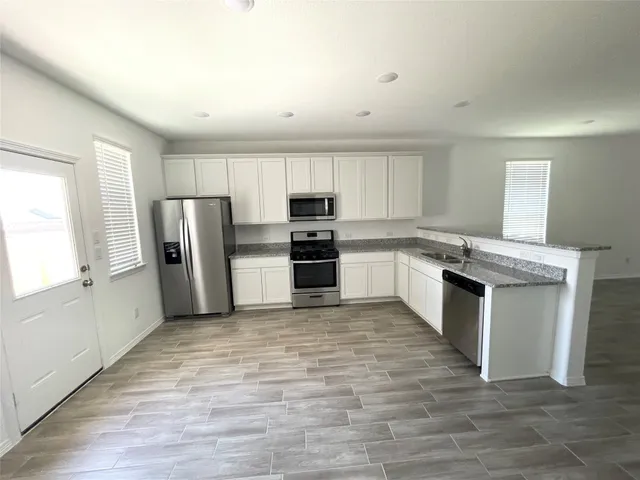 a kitchen with granite countertop a refrigerator and a stove top oven