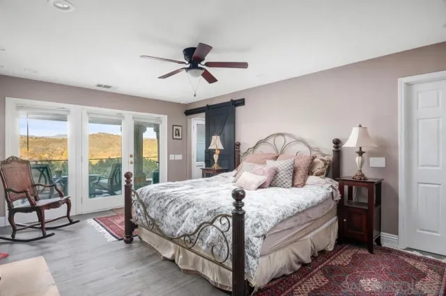 a bedroom with a bed a flat tv screen and a dresser