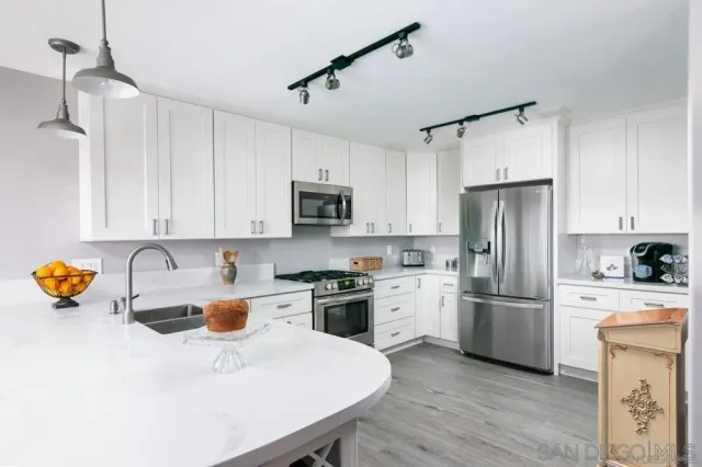 a kitchen with stainless steel appliances granite countertop a sink a stove a refrigerator a center island and cabinets