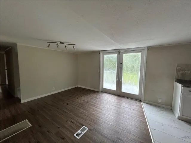 an empty room with wooden floor and windows