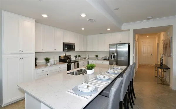 a kitchen with stainless steel appliances granite countertop a refrigerator a stove a sink a dining table and chairs