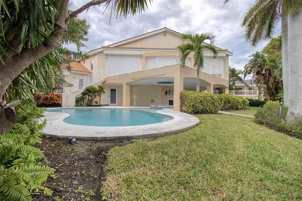 a view of a swimming pool with a yard and palm trees