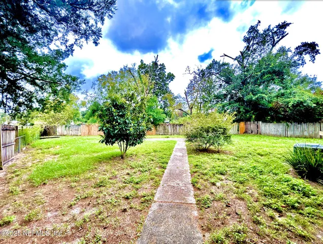 a green field with lots of flowers in front of it