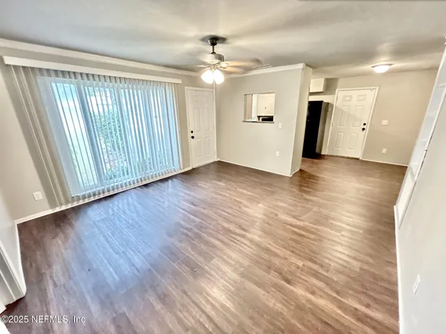 an empty room with wooden floor and a ceiling fan
