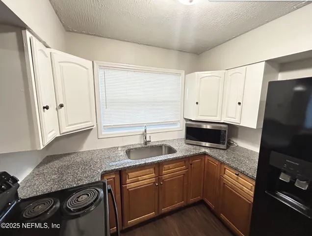 a kitchen with granite countertop a sink stove and refrigerator
