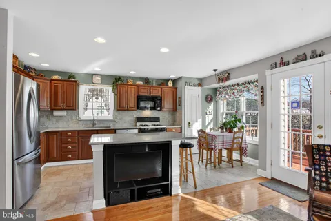 a kitchen with stainless steel appliances granite countertop a stove top oven a sink dishwasher a dining table and chairs with wooden floor