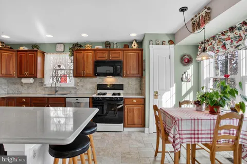 a kitchen with stainless steel appliances granite countertop a kitchen island a table and chairs in it