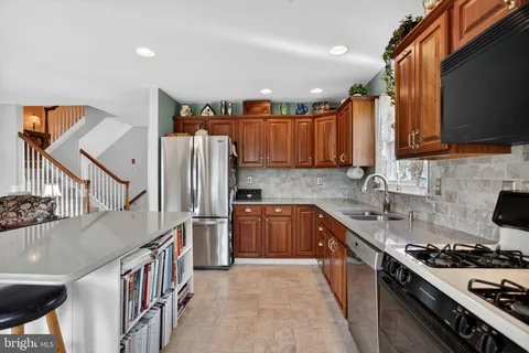 a kitchen with stainless steel appliances granite countertop a stove a sink dishwasher and a refrigerator with wooden floor