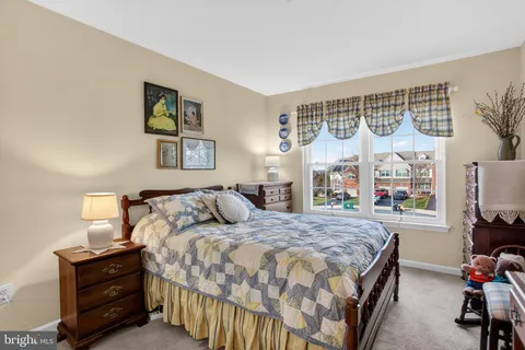 a bedroom with a bed painting on wall and a large window