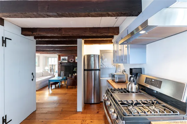 a kitchen with stainless steel appliances granite countertop a stove top oven a dining table and chairs with wooden floor