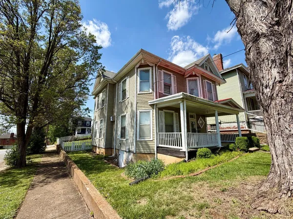 a view of a house with a yard and large tree
