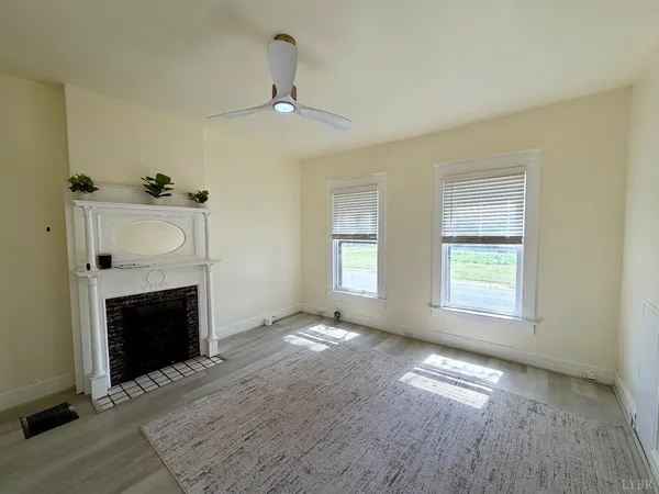 a view of an empty room with window and fireplace