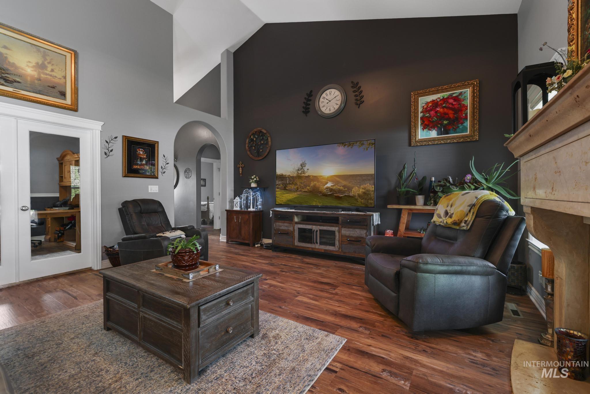 467 Wildrose Loop Twin Falls, ID 83301 - Photo 9 of 46 Living area featuring vaulted ceilings, wood-finish flooring, a stone fireplace, and an arched doorway