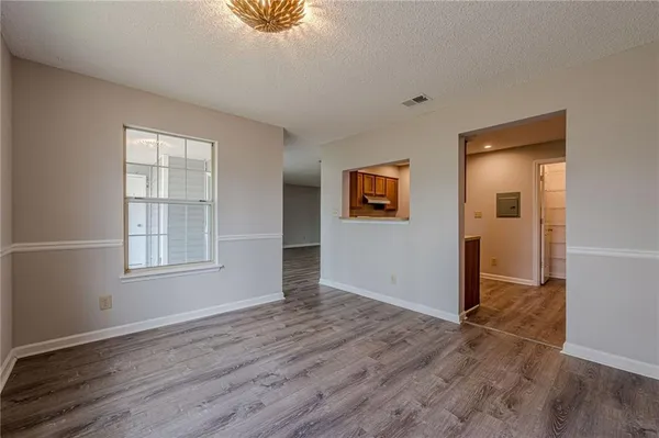 an empty room with wooden floor fan and windows