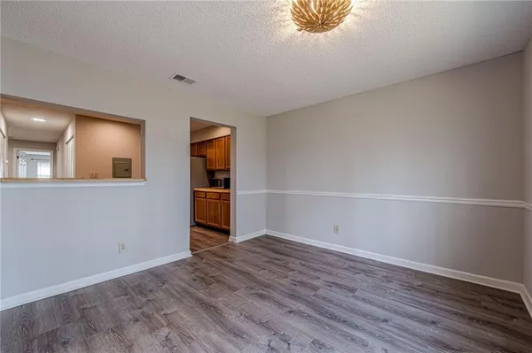 a view of an empty room with wooden floor and a ceiling fan