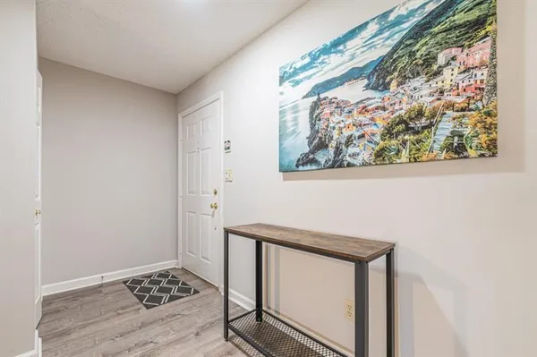 a view of a hallway to a room with wooden floor and a rug