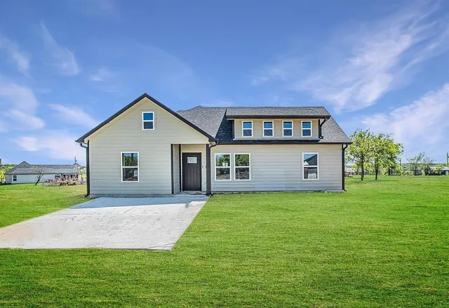 a front view of house with yard and trees in the background