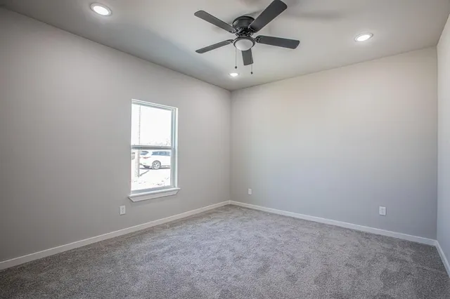 an empty room with a window and a ceiling fan