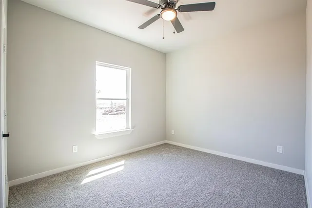 an empty room with a window and a fan