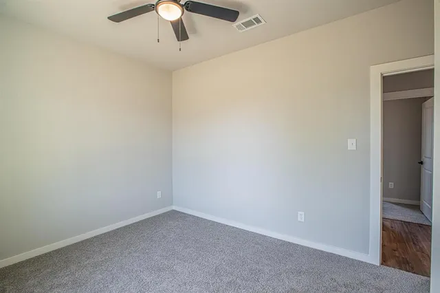 an empty room with a chandelier fan and closet