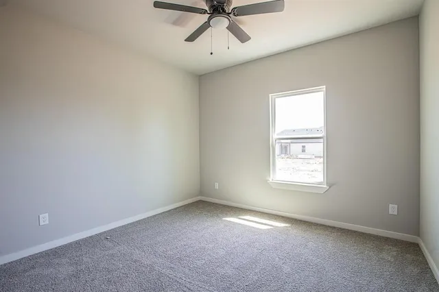 an empty room with a window and a fan