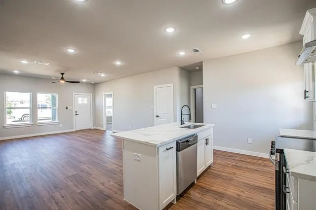 a large kitchen with stainless steel appliances a large counter top a sink and a refrigerator