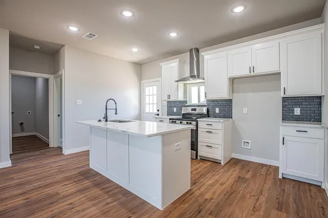a kitchen with white cabinets stainless steel appliances and wooden floor