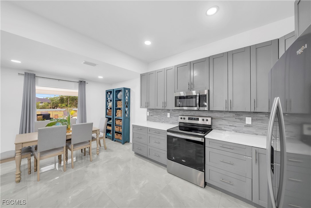 7881 Buckingham Road Fort Myers, FL 33905 - Photo 14 of 49 a kitchen with stainless steel appliances granite countertop a stove top oven a sink a dining table and chairs