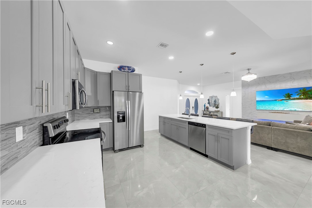 7881 Buckingham Road Fort Myers, FL 33905 - Photo 16 of 49 a kitchen with stainless steel appliances a refrigerator a sink dishwasher a oven with white cabinets and wooden floor