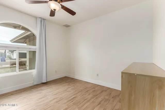 an empty room with a window and ceiling fan