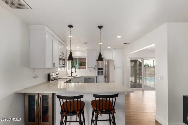 a kitchen with stainless steel appliances kitchen island granite countertop a dining table chairs and white cabinets