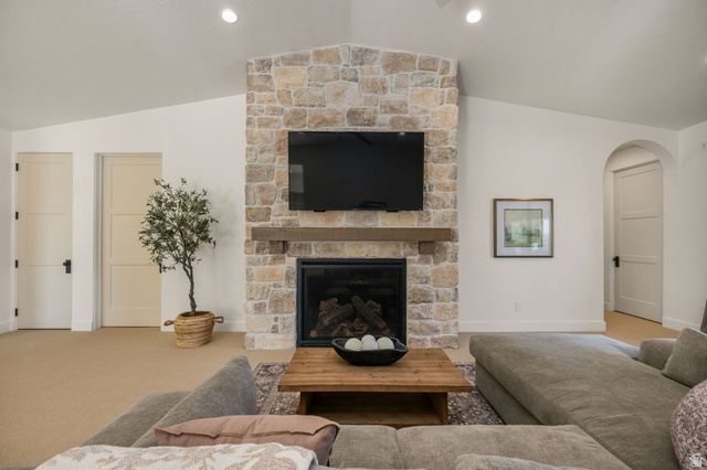4871 South Homestead Way Washington, UT 84780 - Photo 69 of 151 Carpeted living area with arched walkways, vaulted ceiling, and a stone fireplace
