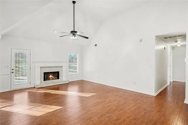 a view of a livingroom with a fireplace a ceiling fan and wooden floor