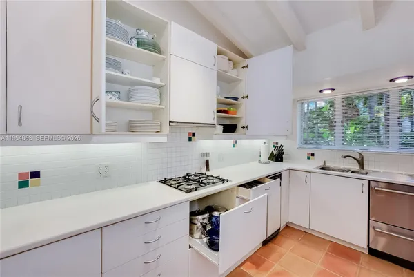 a kitchen with granite countertop a sink a stove and cabinets with wooden floor