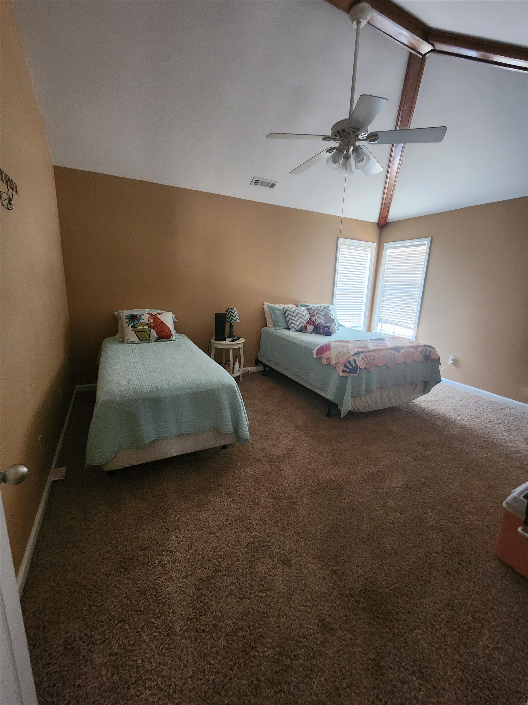 71 Chickasaw Trace Cherokee, AL 35616 - Photo 14 of 19 Vaulted ceiling with exposed wood beams, ceiling fan light fixture, two windows with blinds, and wall-to-wall carpeting