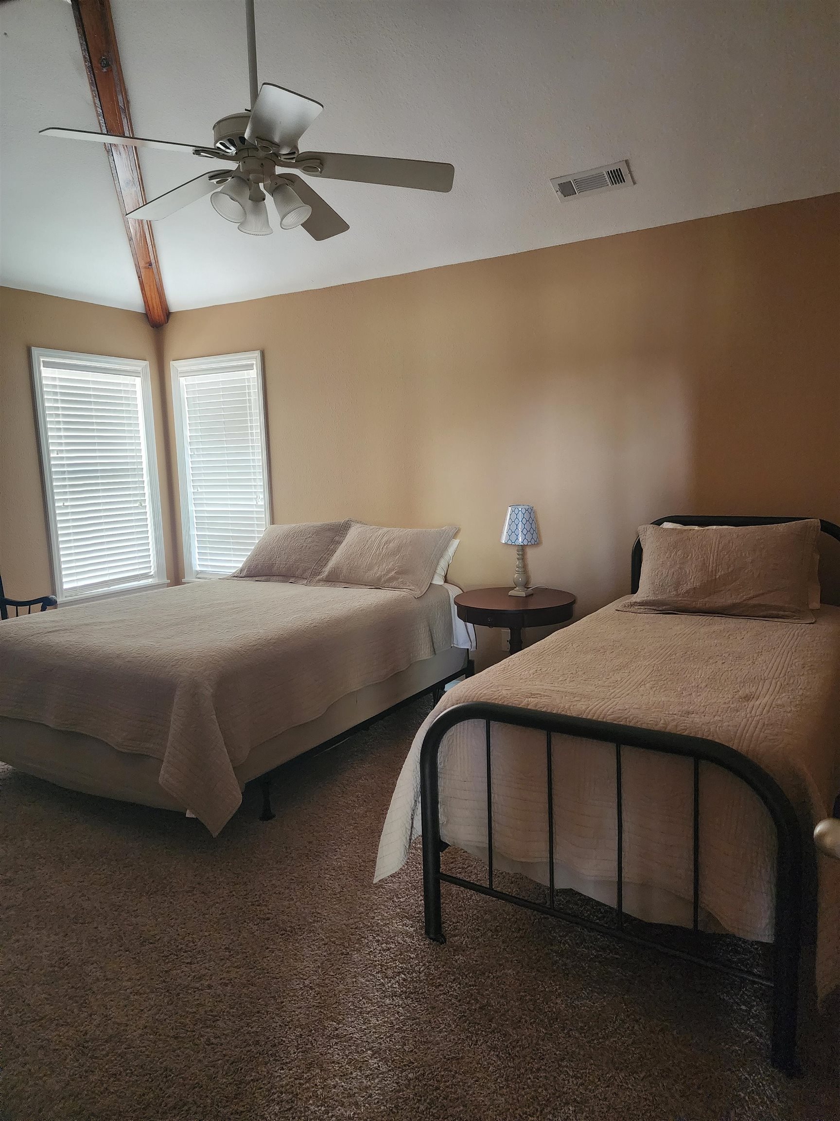 71 Chickasaw Trace Cherokee, AL 35616 - Photo 15 of 19 Carpeted room featuring a vaulted ceiling with exposed wood beams, a ceiling fan with integrated lighting, and two windows with horizontal blinds