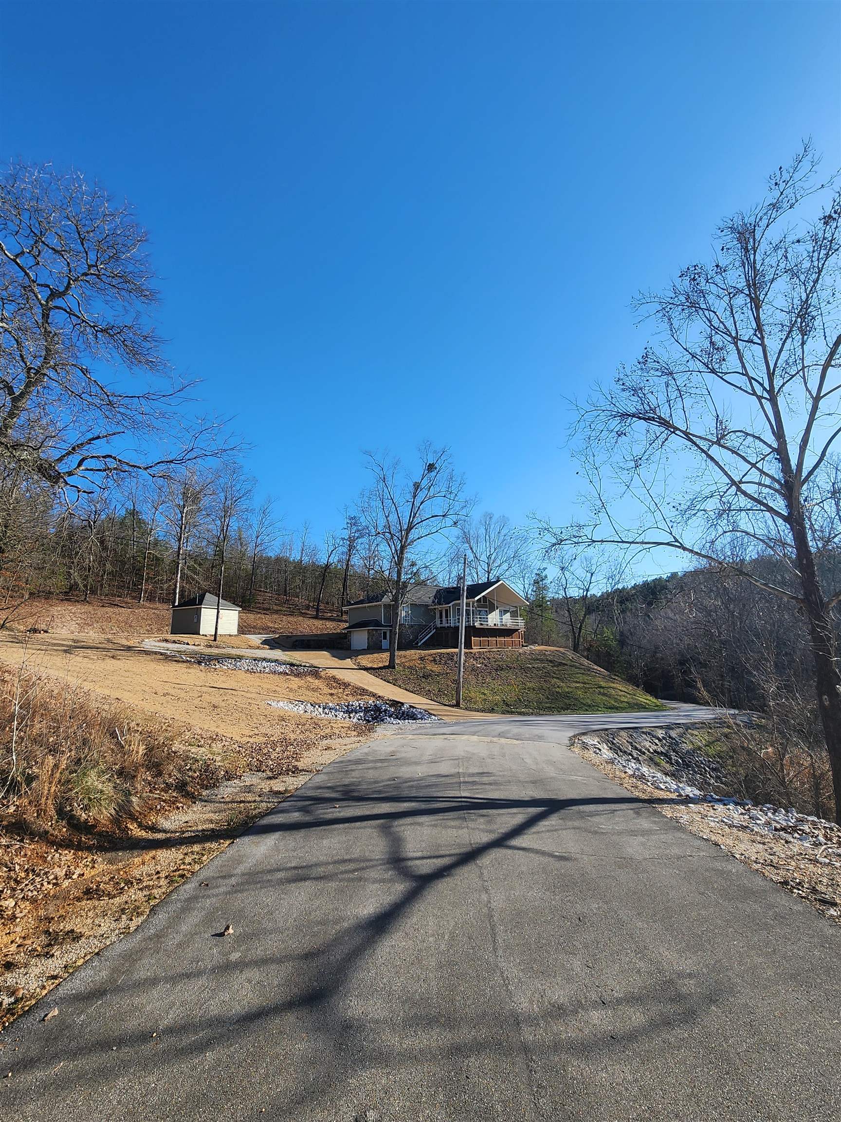 71 Chickasaw Trace Cherokee, AL 35616 - Photo 16 of 19 Asphalt paved driveway leading to a residence with a light-colored siding exterior, an elevated wood deck, and an attached garage