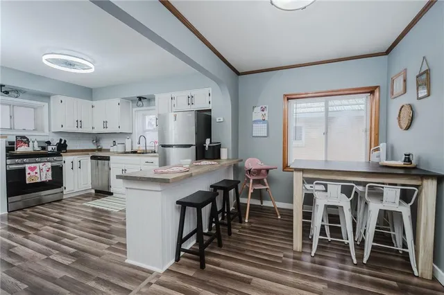 a kitchen with stainless steel appliances granite countertop a table chairs sink and cabinets