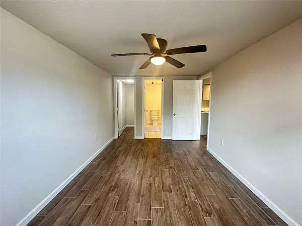 a view of an empty room with a window and wooden floor