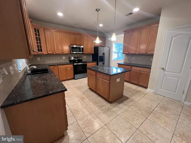a kitchen with stainless steel appliances granite countertop a stove a sink and a refrigerator